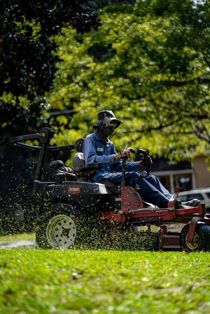 pexels-photo-13630739 Person on a lawn mower cutting grass in a sunny, green park.