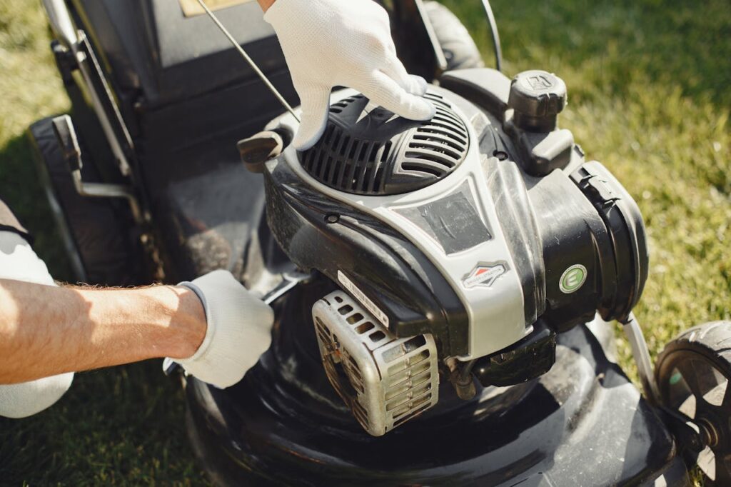 pexels-photo-5163423 Hands in gloves adjusting a lawn mower outdoors, perfect for gardening themes.